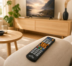 Afstandsbediening met grote knoppen op beige bank in warme woonkamer — SeniorSlim