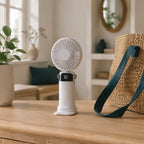Opvouwbare handventilator in wit op een sidetable naast een geweven rieten tas